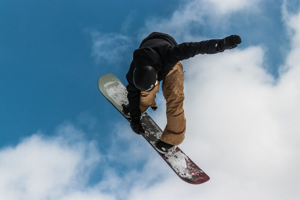 Best Action Cameras man in black jacket and brown pants riding white and red snowboard