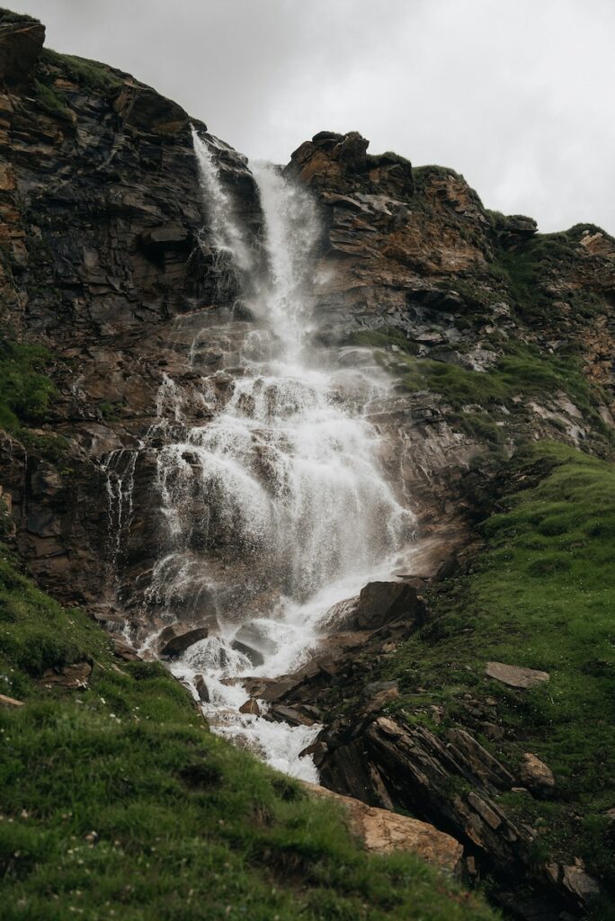 a very tall waterfall in the middle of a lush green field