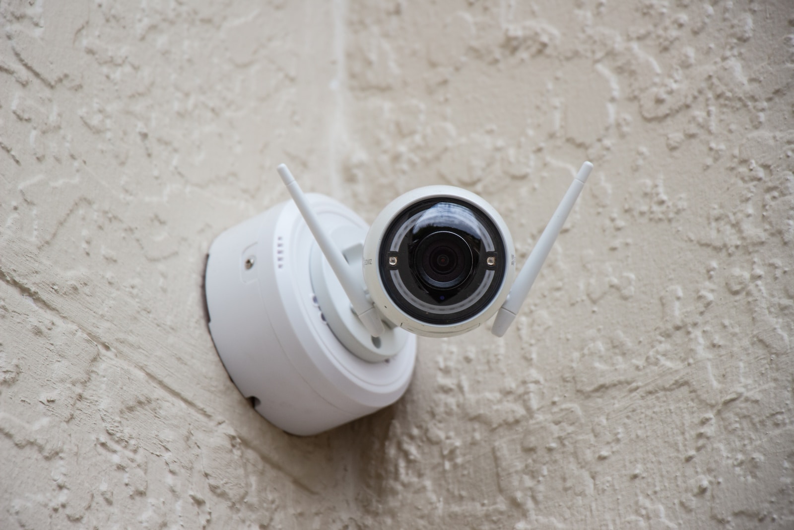 Wireless Security Cameras white surveillance camera hanging on wall