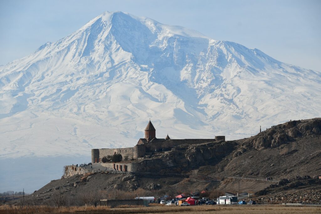 a castle on a hill with a snow covered mountain in the background
