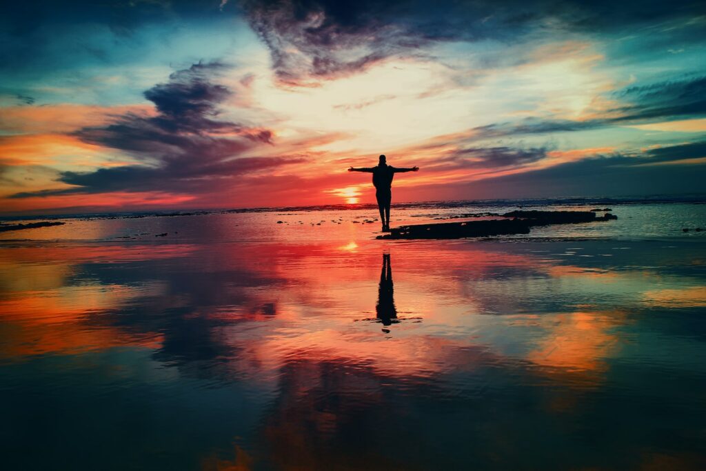 Sunrise Photography silhouette of person standing on rock surrounded by body of water