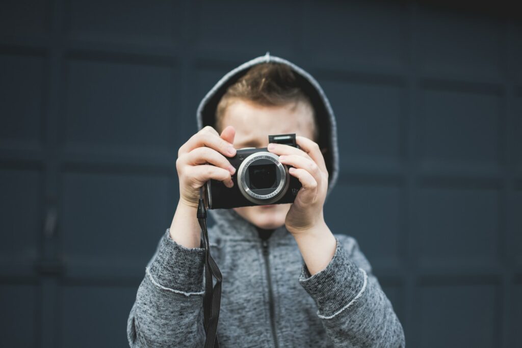 Point and Shoot Camera - person in grey hoodie holding up camera over face