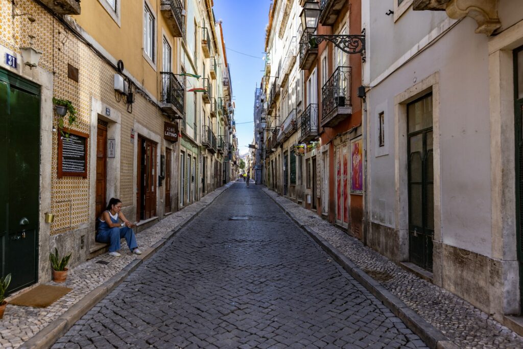 a person sitting on a cobblestone street in a city