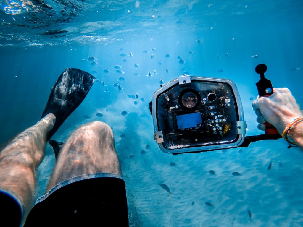 Underwater Cameras man bathing under the sea while holding black camera